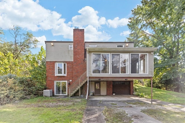 back of house with central air condition unit, a carport, a lawn, and a garage