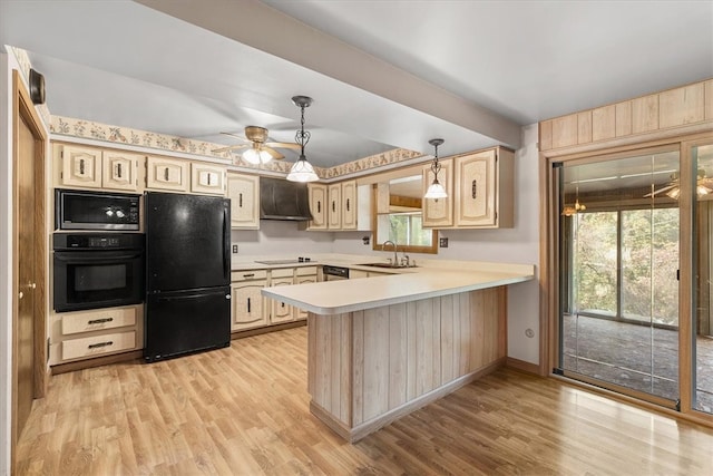 kitchen featuring sink, kitchen peninsula, decorative light fixtures, black appliances, and light wood-type flooring