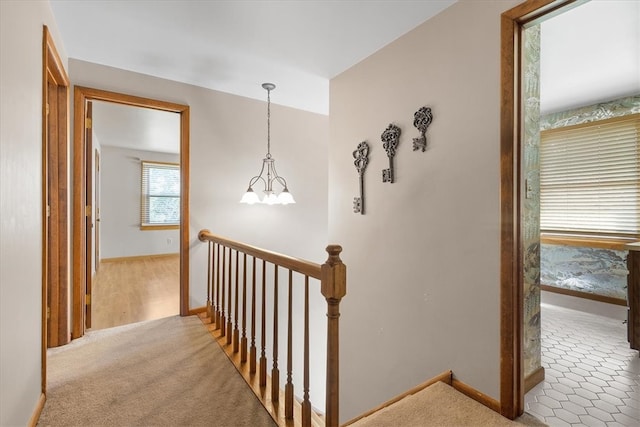 hallway featuring a notable chandelier and carpet flooring