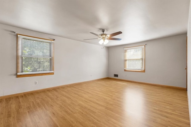 spare room featuring ceiling fan, light wood-type flooring, and plenty of natural light