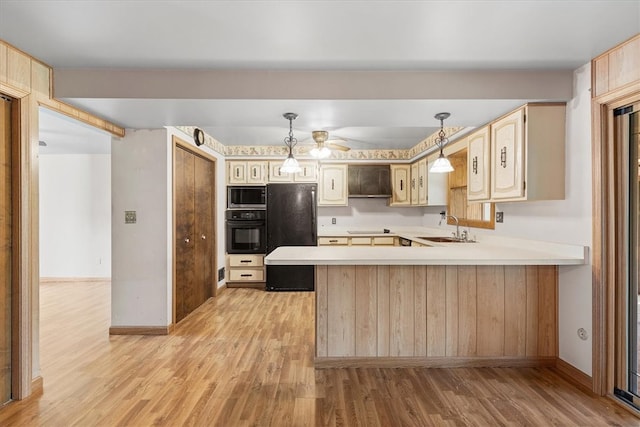 kitchen featuring light wood-type flooring, sink, kitchen peninsula, hanging light fixtures, and black appliances