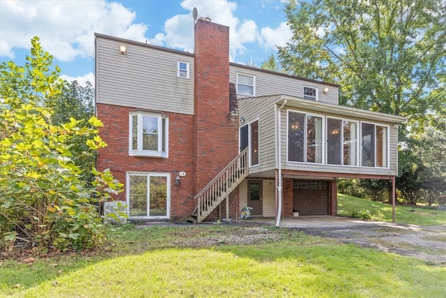 rear view of house with a garage, a sunroom, and a lawn