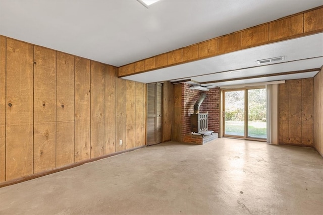 unfurnished living room featuring wooden walls and a wood stove