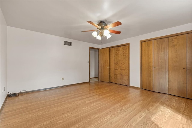 unfurnished bedroom featuring ceiling fan, two closets, and light hardwood / wood-style floors