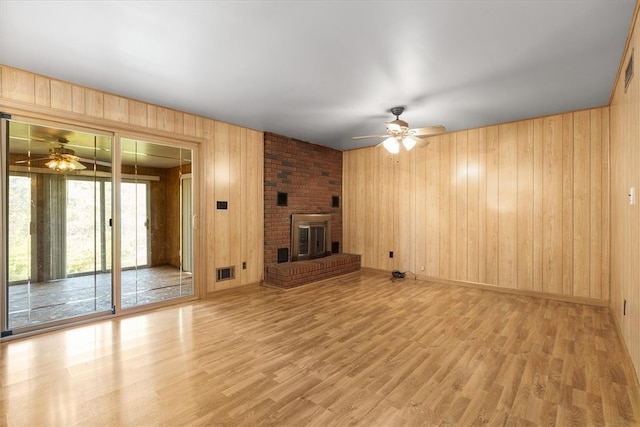 unfurnished living room with wooden walls, ceiling fan, and wood-type flooring