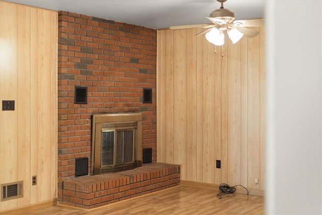 unfurnished living room with a fireplace, wood walls, and hardwood / wood-style floors