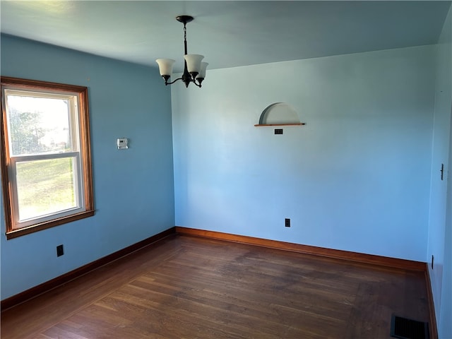 unfurnished room with dark hardwood / wood-style flooring and an inviting chandelier