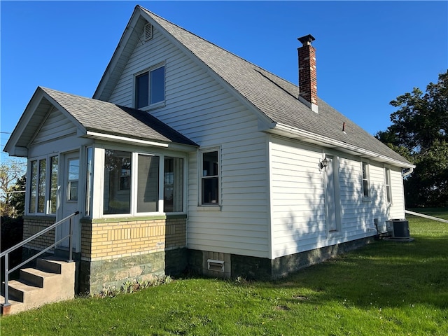 view of side of property featuring a sunroom, a yard, and central air condition unit