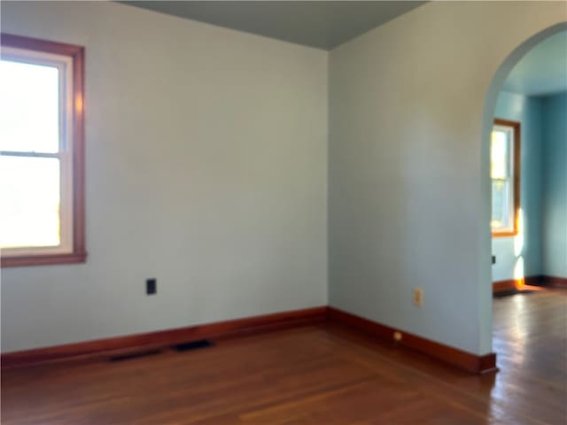 unfurnished room featuring a wealth of natural light and dark hardwood / wood-style floors