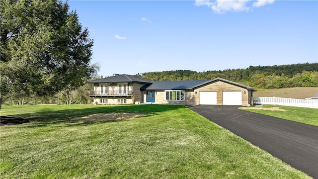 view of front facade featuring driveway, a front lawn, an attached garage, and fence