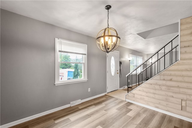 entryway with an inviting chandelier, a healthy amount of sunlight, and hardwood / wood-style flooring