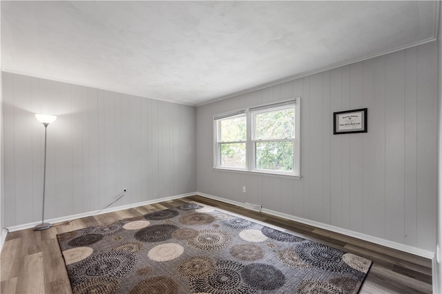 spare room featuring dark wood-type flooring and wood walls