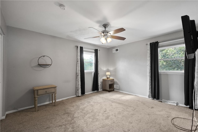 carpeted spare room featuring ceiling fan and a wealth of natural light