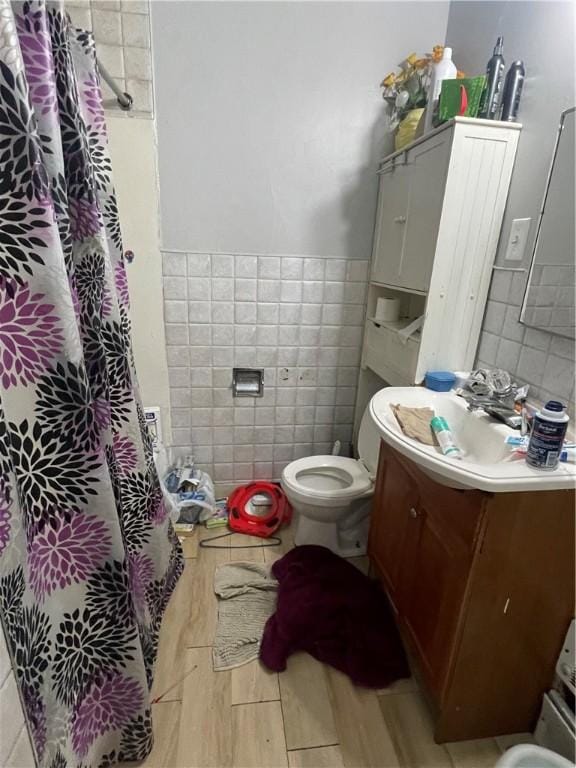 full bathroom featuring curtained shower, tile walls, toilet, and vanity