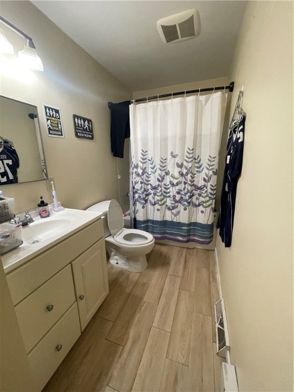 bathroom featuring wood-type flooring, a shower with curtain, vanity, and toilet