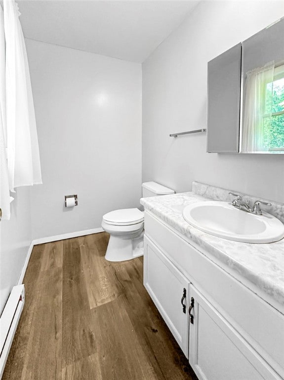 bathroom featuring a baseboard radiator, hardwood / wood-style flooring, vanity, and toilet