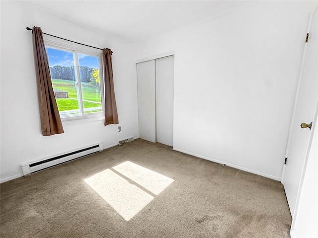 unfurnished bedroom featuring carpet floors, a closet, and a baseboard heating unit