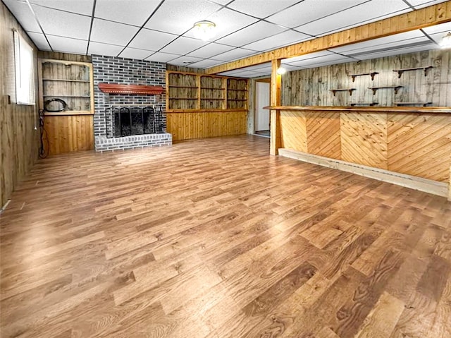 interior space featuring built in shelves, wood walls, hardwood / wood-style floors, and a paneled ceiling