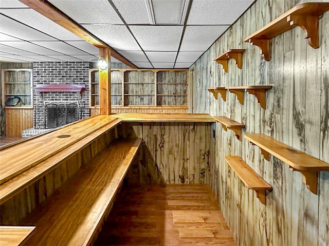 bar with a drop ceiling, hardwood / wood-style flooring, and wooden walls