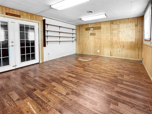 spare room featuring hardwood / wood-style flooring, wooden walls, and french doors