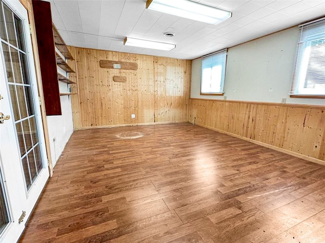 unfurnished room featuring a healthy amount of sunlight, wood walls, and wood-type flooring