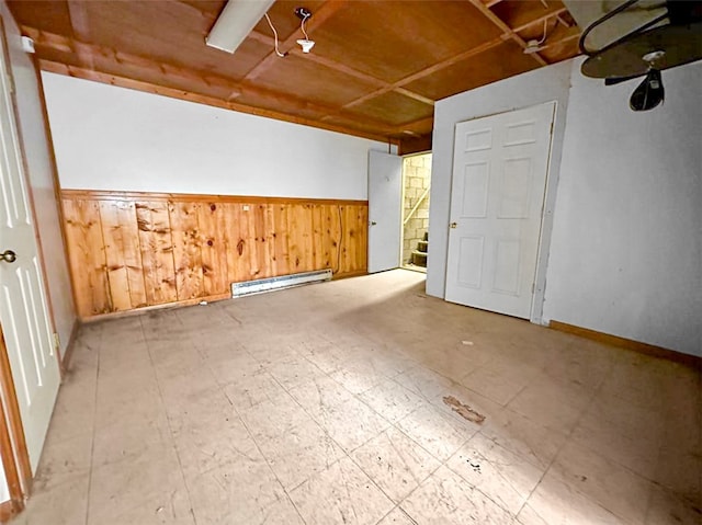 unfurnished room with wooden walls and a baseboard heating unit