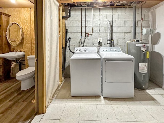 laundry room with water heater, washing machine and dryer, and light tile patterned flooring