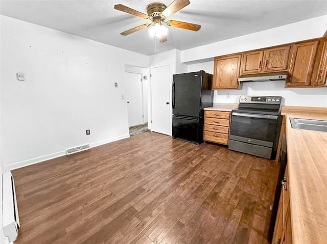 kitchen featuring ceiling fan, exhaust hood, hardwood / wood-style floors, black fridge, and electric stove