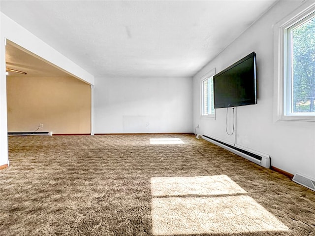 unfurnished living room featuring carpet flooring, baseboard heating, and a wealth of natural light