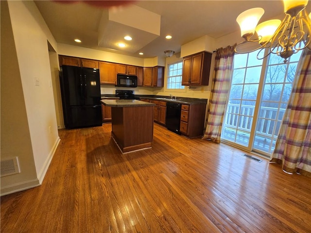 kitchen featuring sink, dark hardwood / wood-style floors, a notable chandelier, black appliances, and a kitchen island