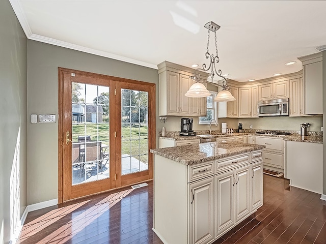 kitchen with light stone countertops, appliances with stainless steel finishes, hanging light fixtures, and dark hardwood / wood-style flooring