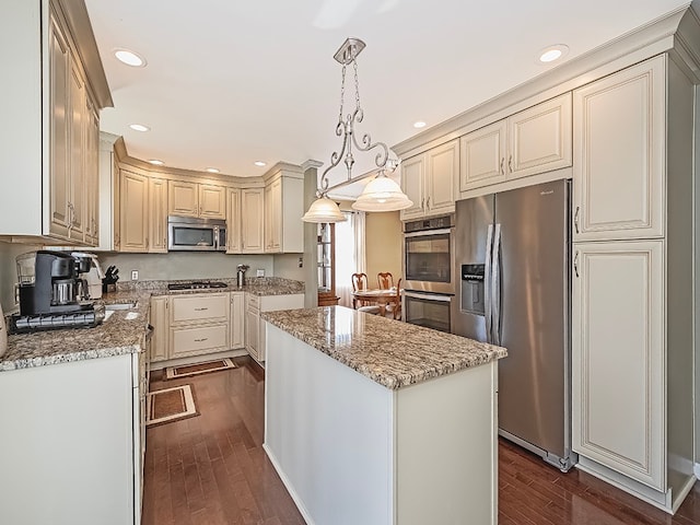 kitchen with decorative light fixtures, appliances with stainless steel finishes, dark hardwood / wood-style flooring, and a kitchen island