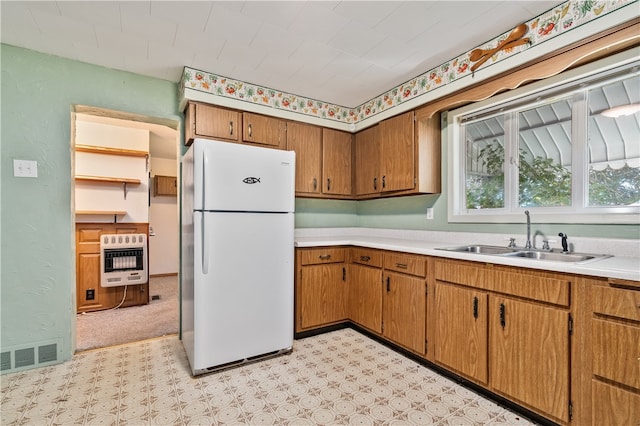 kitchen featuring heating unit, white fridge, and sink