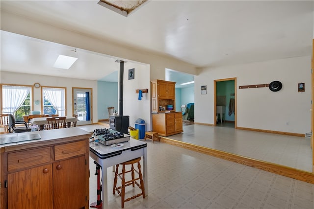 kitchen featuring a wood stove, sink, kitchen peninsula, a breakfast bar area, and a skylight