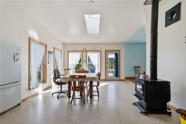 dining area featuring a skylight and a wood stove