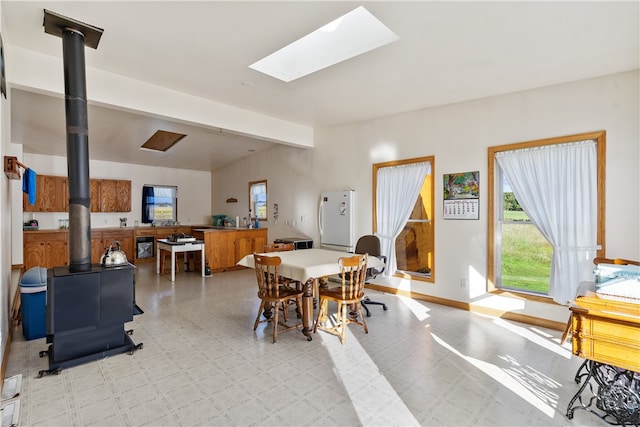 dining room featuring beamed ceiling and a skylight