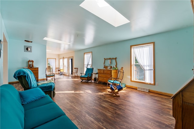 living room featuring dark wood-type flooring, plenty of natural light, and a skylight