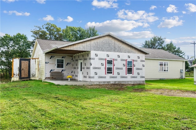 rear view of house featuring a patio, a lawn, and a storage unit