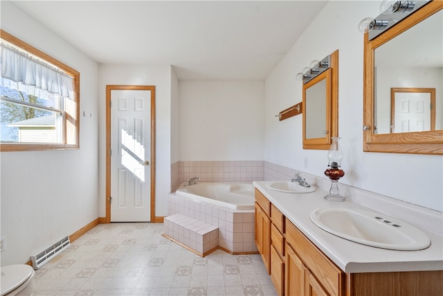 bathroom featuring vanity, toilet, and tiled bath