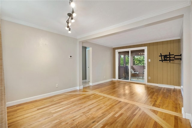 spare room with crown molding, wood walls, and wood-type flooring