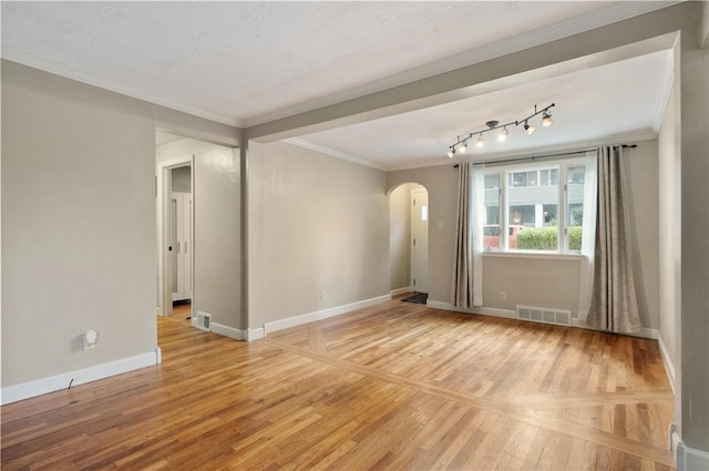 spare room featuring ornamental molding, light wood-type flooring, and a textured ceiling