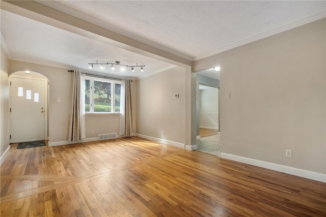 spare room with light hardwood / wood-style floors, crown molding, and a textured ceiling