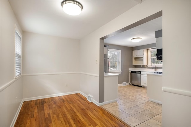 kitchen with dishwasher, light hardwood / wood-style floors, and white cabinets