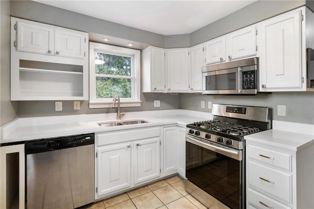 kitchen featuring light tile patterned flooring, appliances with stainless steel finishes, sink, and white cabinetry