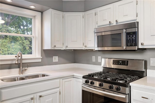 kitchen with stainless steel appliances, white cabinets, and sink