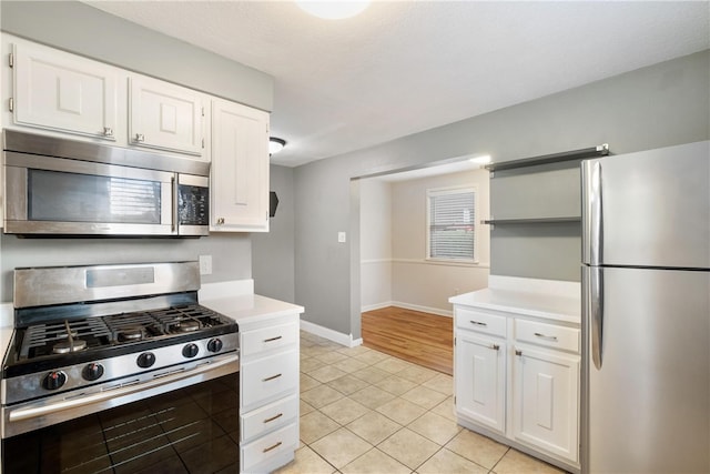 kitchen featuring stainless steel appliances, light tile patterned floors, and white cabinetry