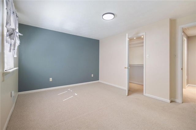 unfurnished bedroom with light carpet, a spacious closet, and a closet