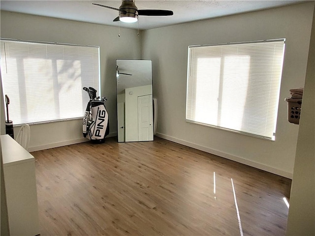 spare room featuring baseboards, wood finished floors, and ceiling fan