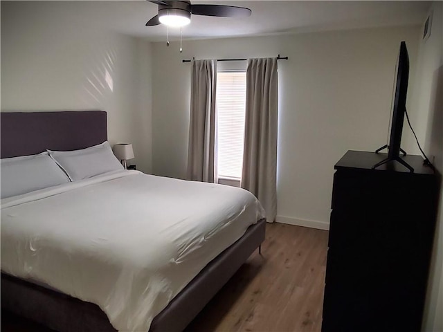 bedroom with light wood-style floors, ceiling fan, and baseboards