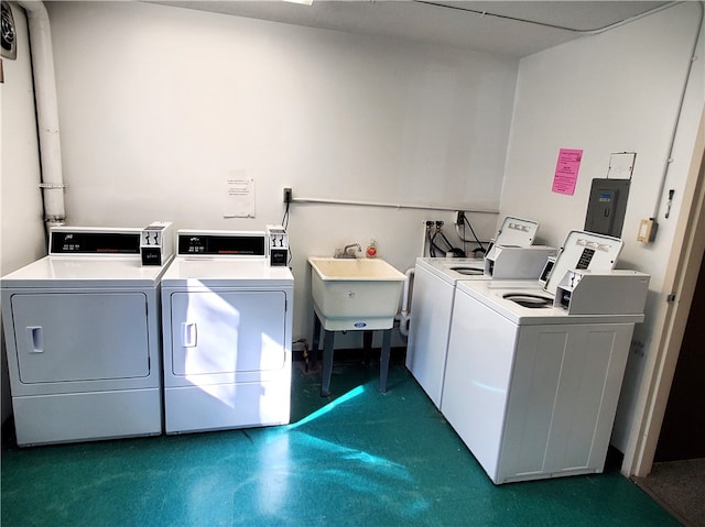 laundry room with electric panel, washer and dryer, and sink